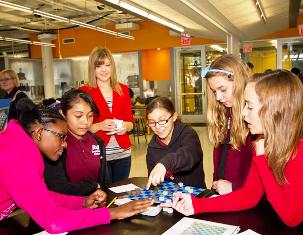 ASU engineering students Kelsey Stopkey (center) and Julia King (far right) gather with six-grade students from ASU Preparatory Academy to examine a prototype for a game called Battle Plates, designed to teach geological concepts related to plate tectonics. It was one of several toy and game designs the engineering students and youngsters collaborated on. Photo: Jessica Slater/ASU