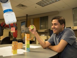 Tathagata Chakraborti and industrial robot Kramer stack building blocks to fork the words "Yochan" and "plan."