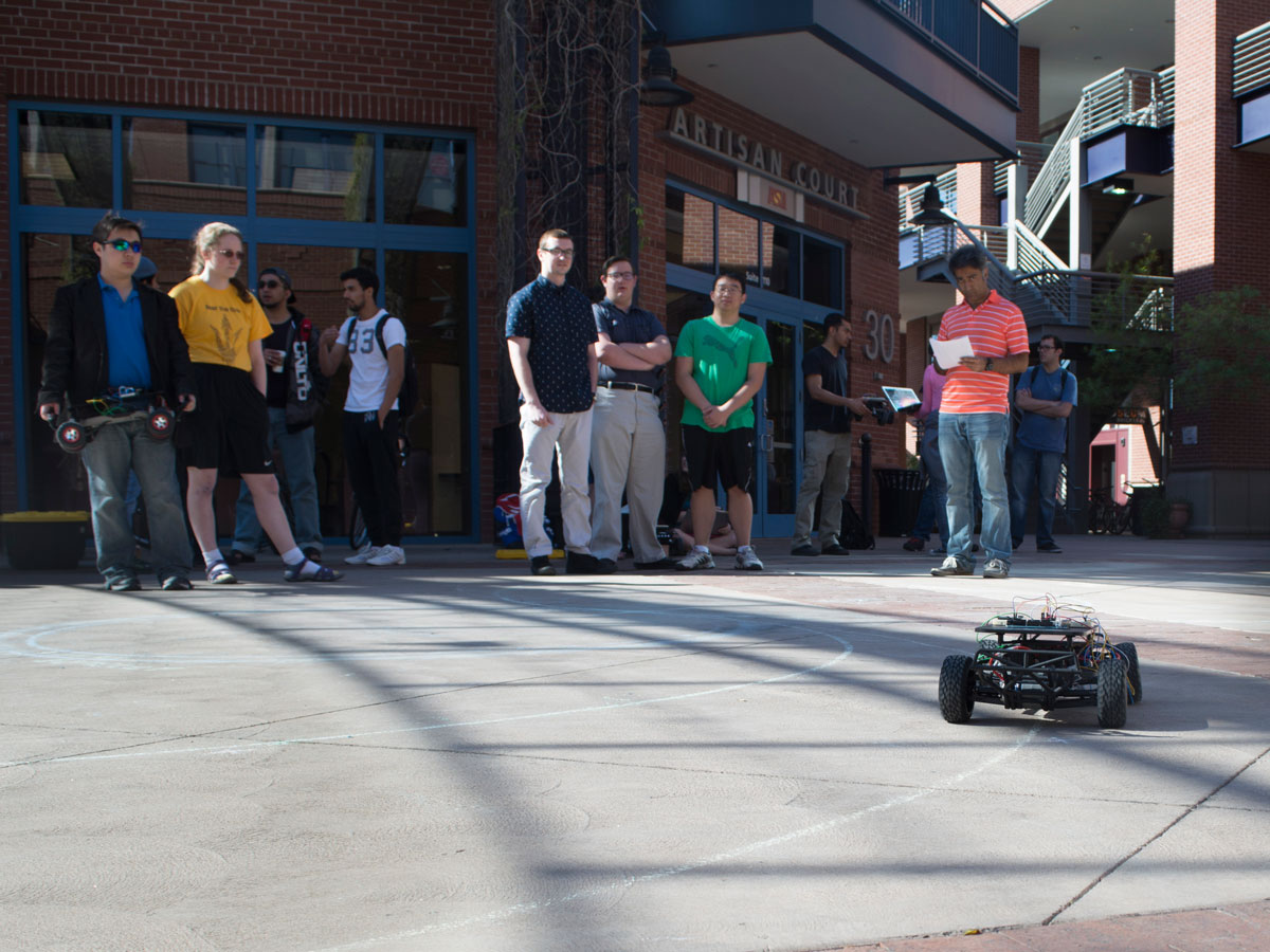 Students and teaching assistants watch a self-navigating car demonstration outside Brickyard Artisan Court on April 1, 2016.