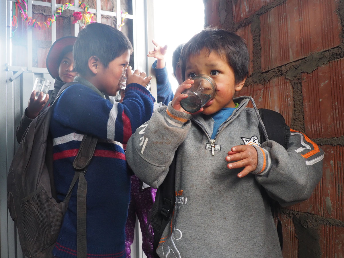 The kids from Huillcapata try the new filtered water during the education event.