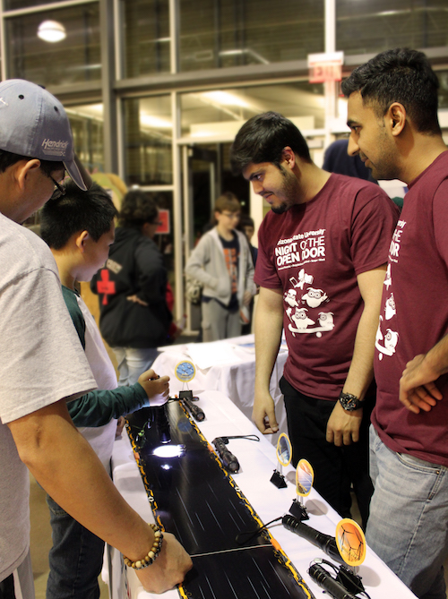 Photo of two students demonstrating solar race cars with a caption of "Ussama Khalid Barki (left) and Usman Salahuddin (right) explain how photovoltaics could change the energy situation in their home country at Night of the Open Door – Polytechnic. Photographer Erika Gronek/ASU"
