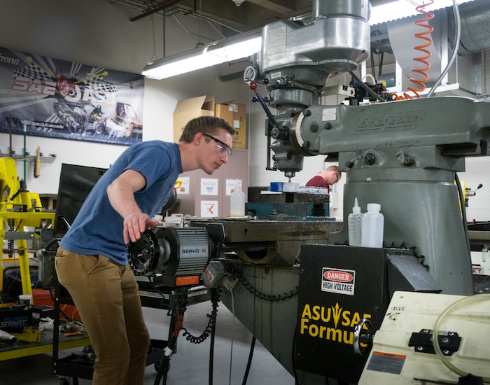 Photo of student working on machine in shop. Caption is "Sean Berties, who worked on the chassis crew for ASU’s Formula SAE race car team, is shown operating a mill to machine the vehicles brake pedal. About 60 students made contributions to the design and construction of the car. Photographer: Alexander Nie/ASU"