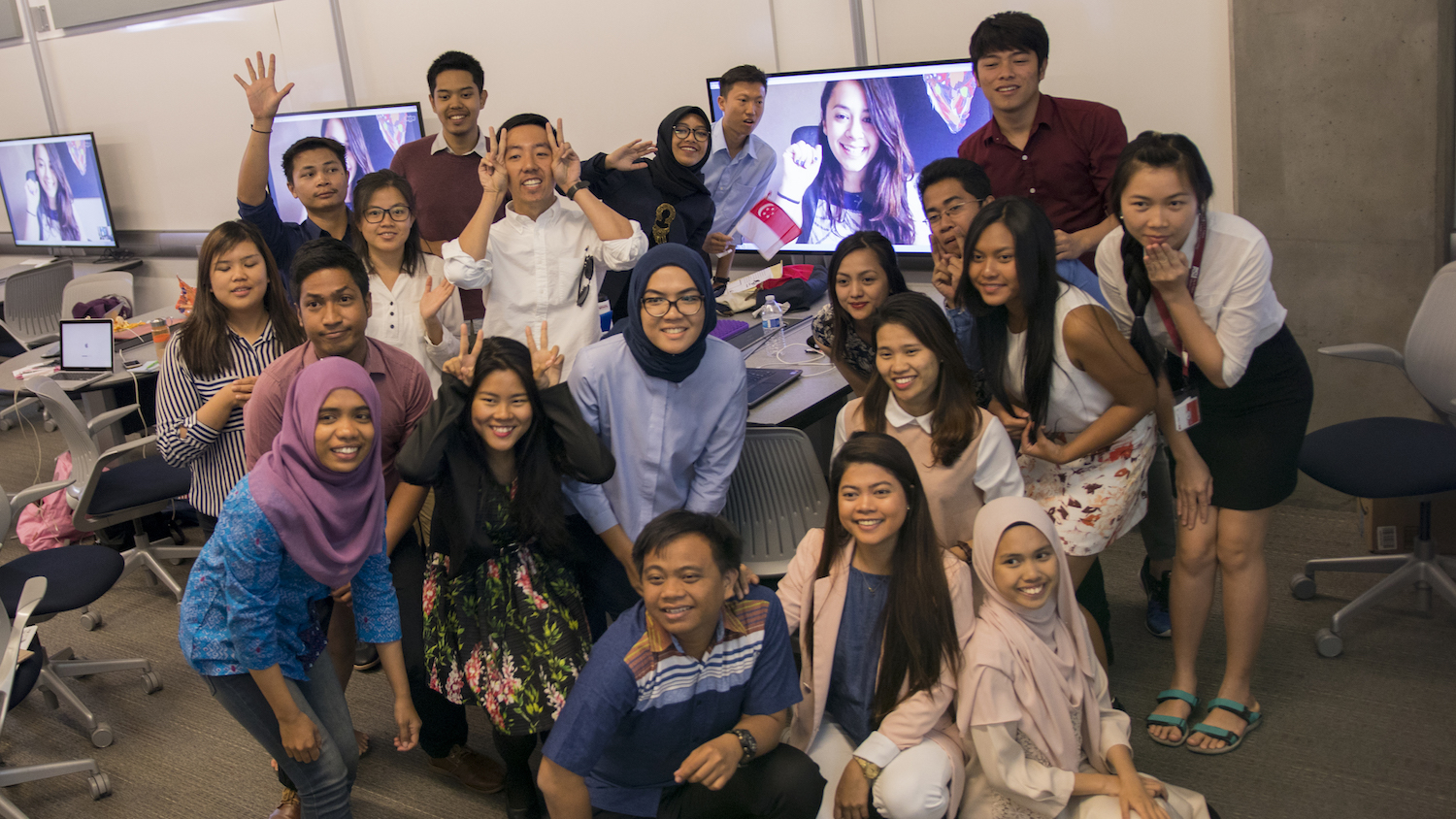 Photo of a large group of people posing for photo with a computer monitor on behind them with a caption of "Students from YSEALI Skyping with a social enterprise expert. Photographer: Marco-Alexis Chaira/ASU"