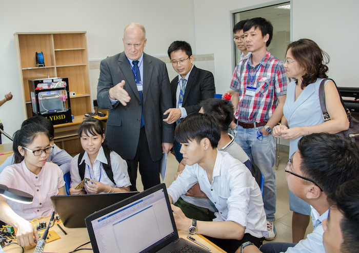 Photo of students and officials gathered around a computer