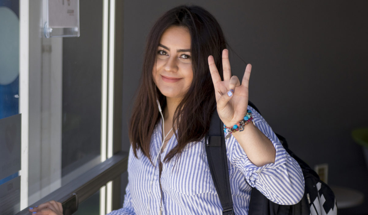 Photo of a girl holding her hand up making the ASU pitchfork sign. Caption: An engineering Sun Devil displays her pride on the first day of classes. Photographer: Marco-Alexis Chaira/ASU