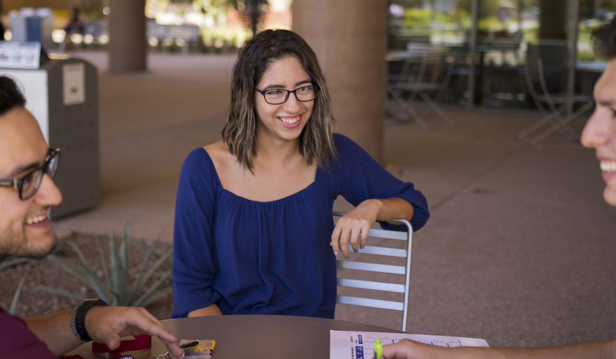 Photo of a girl in a blue shirt sitting at a table. Caption: Sun Devils making connections and friends on the first day of classes. Photographer: Marco-Alexis Chaira/ASU