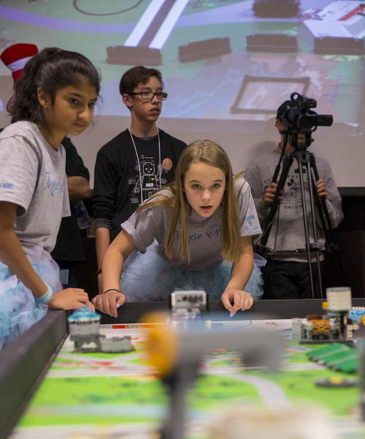 Photo of two girls watching robots on a table. Caption: The Arizona FIRST® LEGO® League 2018 state championship was held January 13-14, 2018, with 92 teams and more than 750 kids qualifying. Photographer: Jessica Hochreiter/ASU