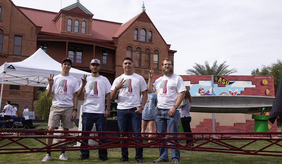 Photo of four students behind a steel bridge. Caption: he Fulton Schools steel bridge team flashes the ASU Sun Devils pitchfork hand sign during the public exhibit on campus before the start of the ASCE student competitions. From left to right are Bill Selby, Mohammad Alsmadi, Jose Gamez and Francisco Camou. Said team captain Gamez: “When I was a high school student I recall watching videos about the steel bridge competition and just being in awe with how team members built their bridges with such ease and great coordination. Never did I think that I would be a project manager for such a team one day.” Photographer: Erika Gronek/ASU