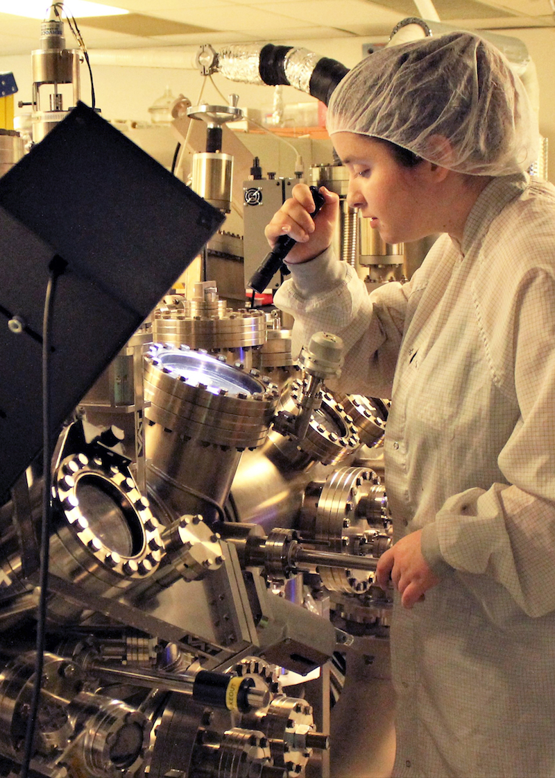 girl in lab coat looking at items with a flashlight