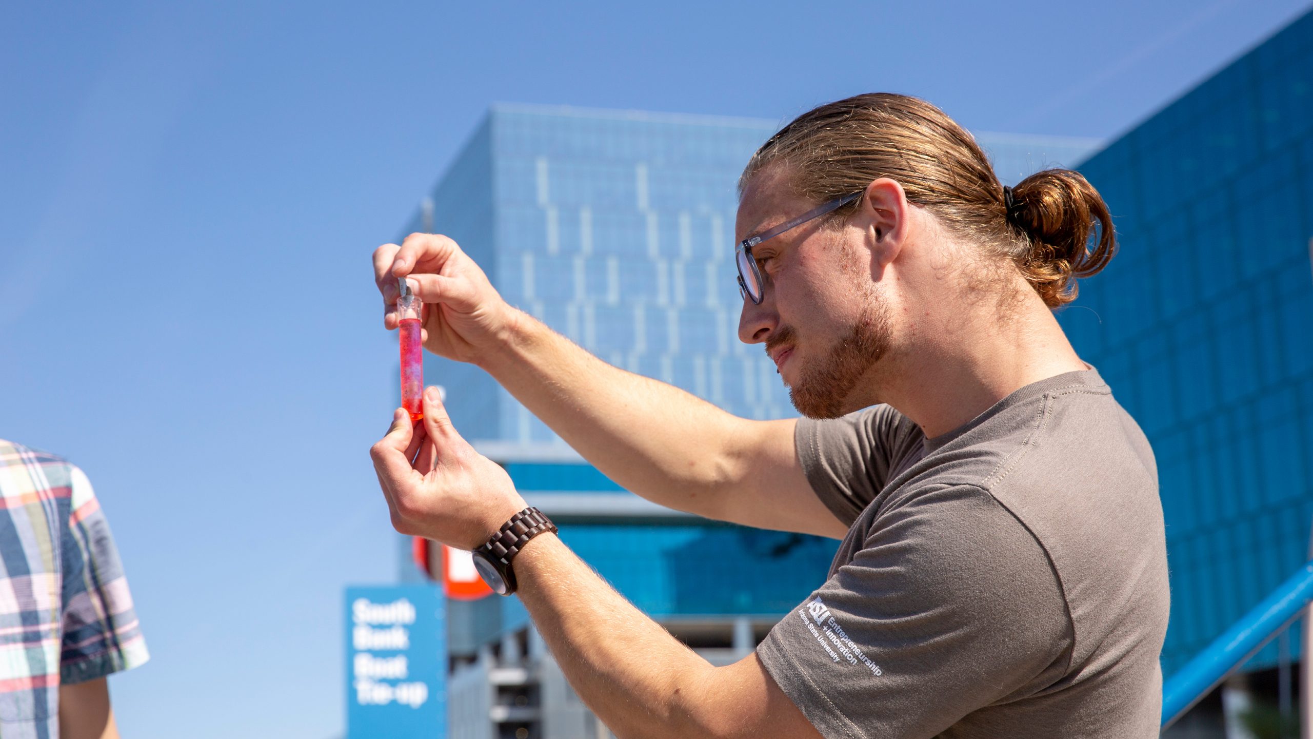 Daniel Hoop holding a vile of pinkish tintted water as part of an EPICS project
