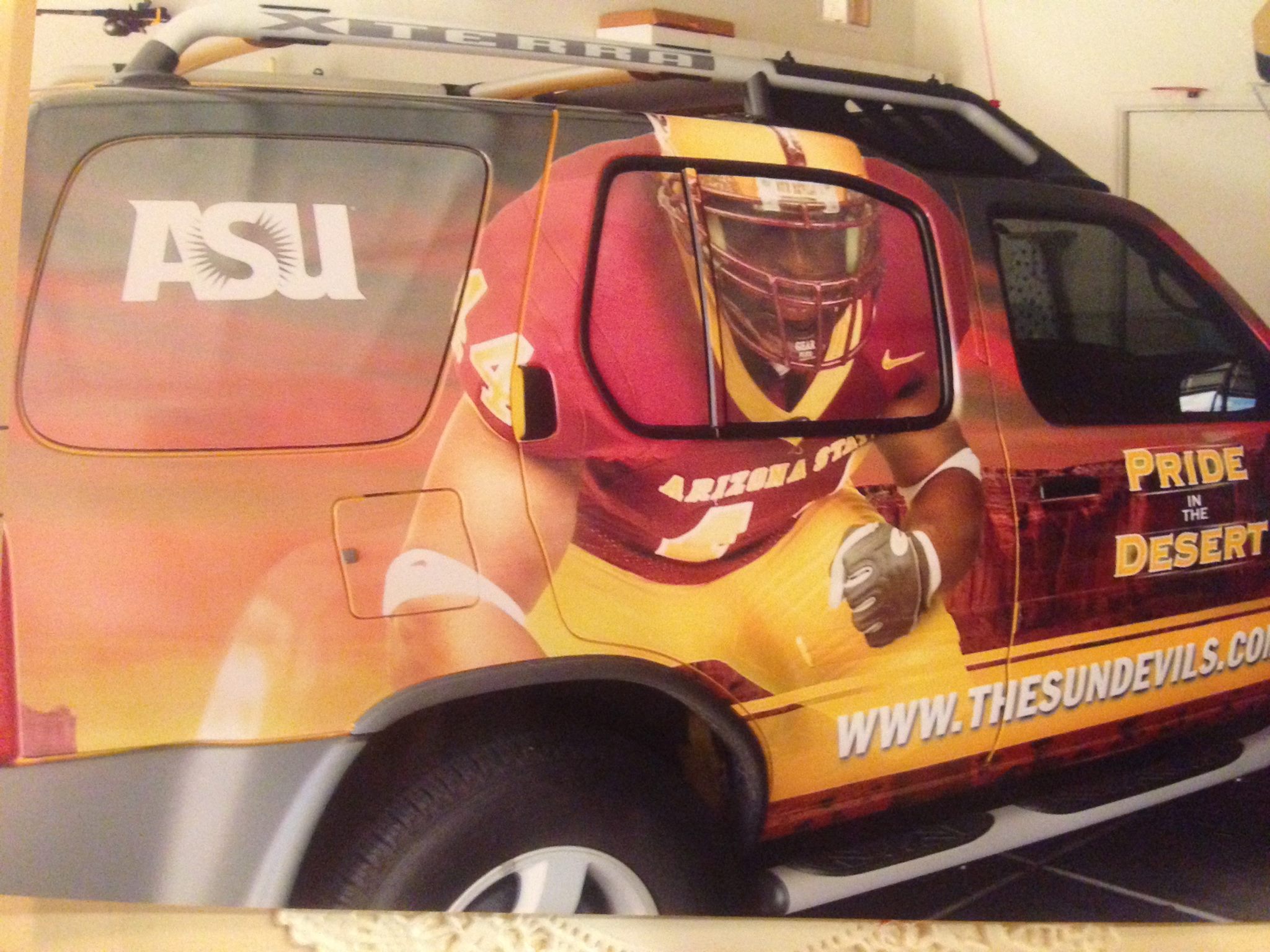 A Nissa X-Terra vehicle covered in a wrap featuring an ASU football player