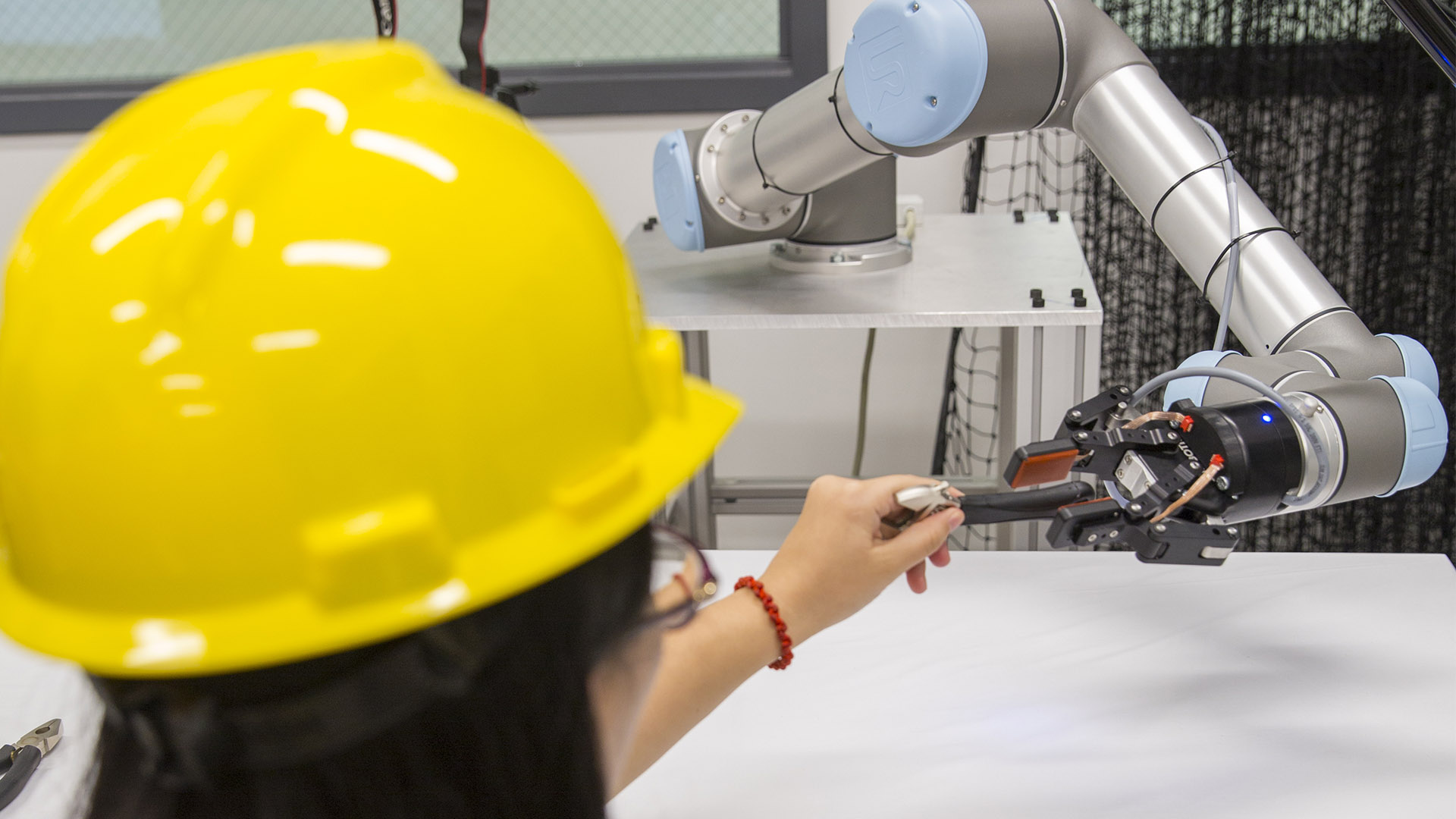 a student in a hard hat working with a robotic arm