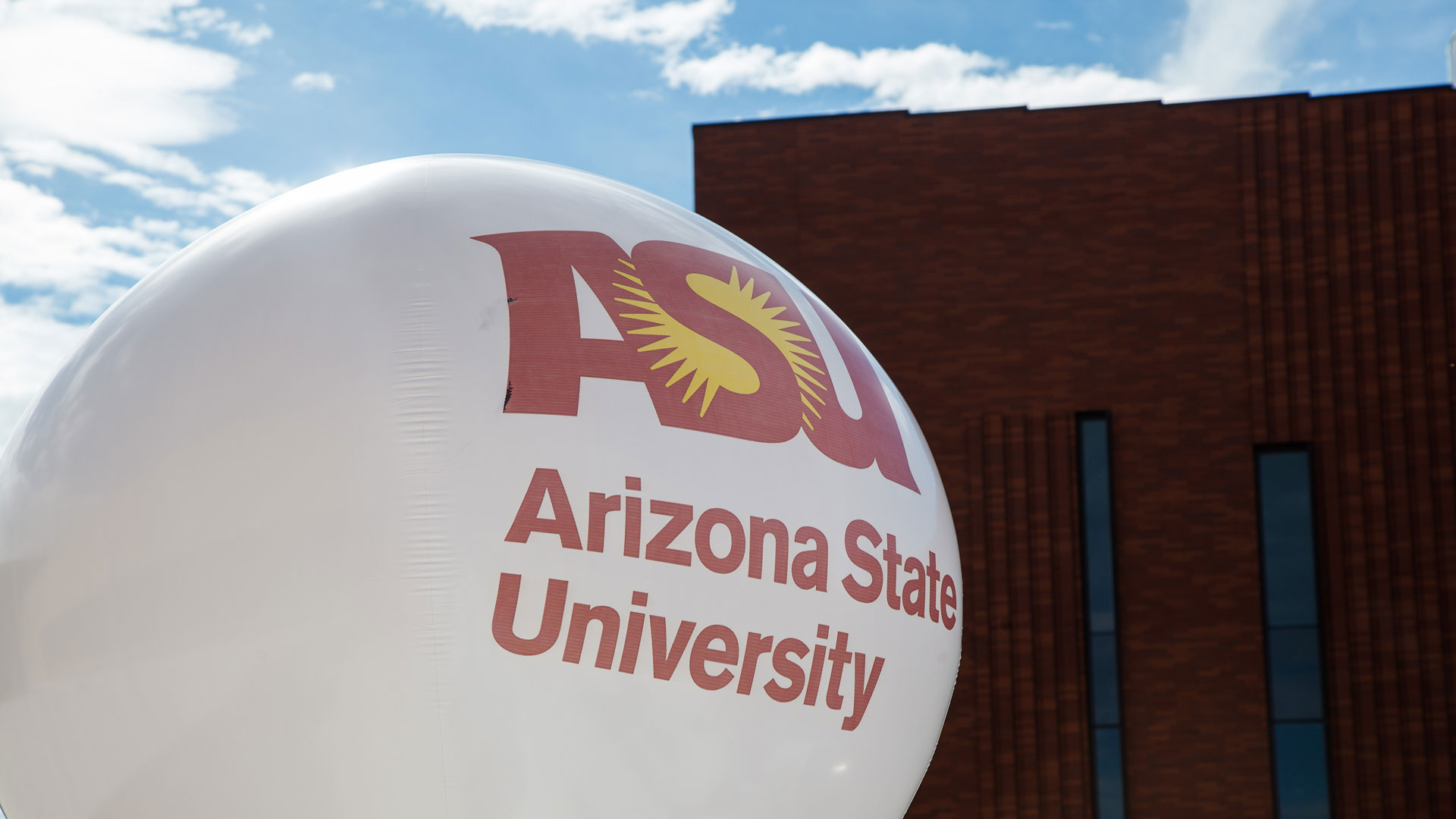A large white balloon with Arizona State University printed on it, pictured in front of a building on the ASU Tempe campus.