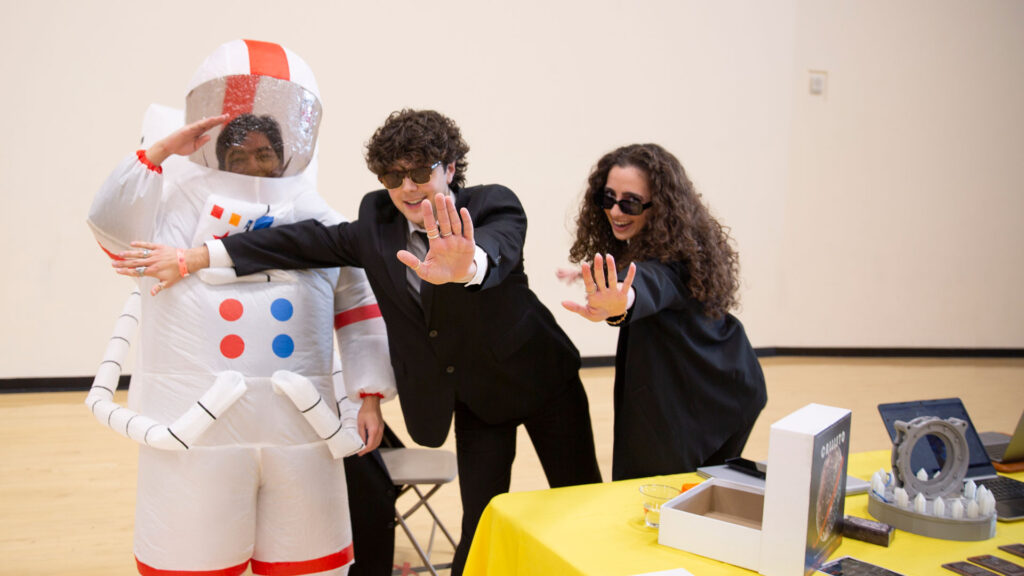 A group of students at the Capstone Showcase, including one in an inflatable astronaut costume.