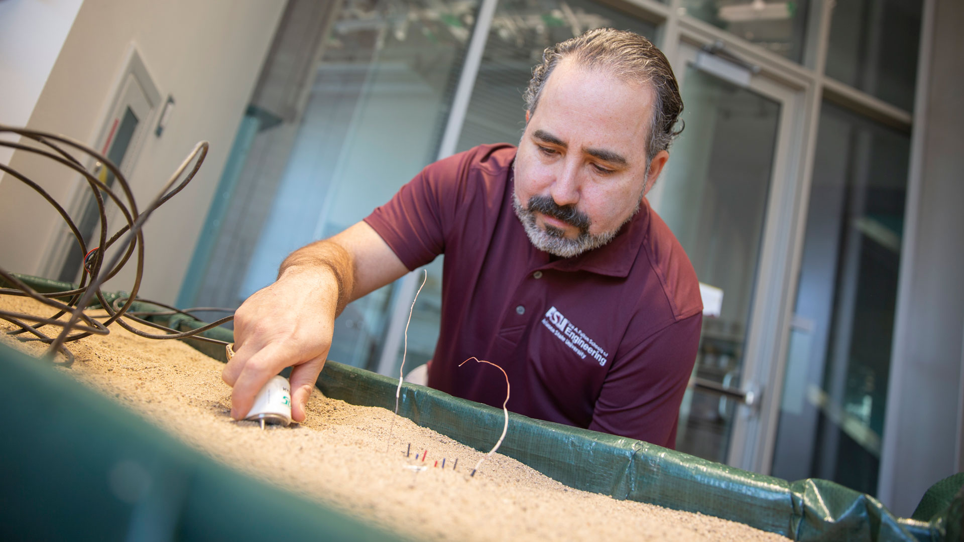 ASU researcher Enrique Vivoni works with a sensor and container of sand in the Hydrology Research Lab.
