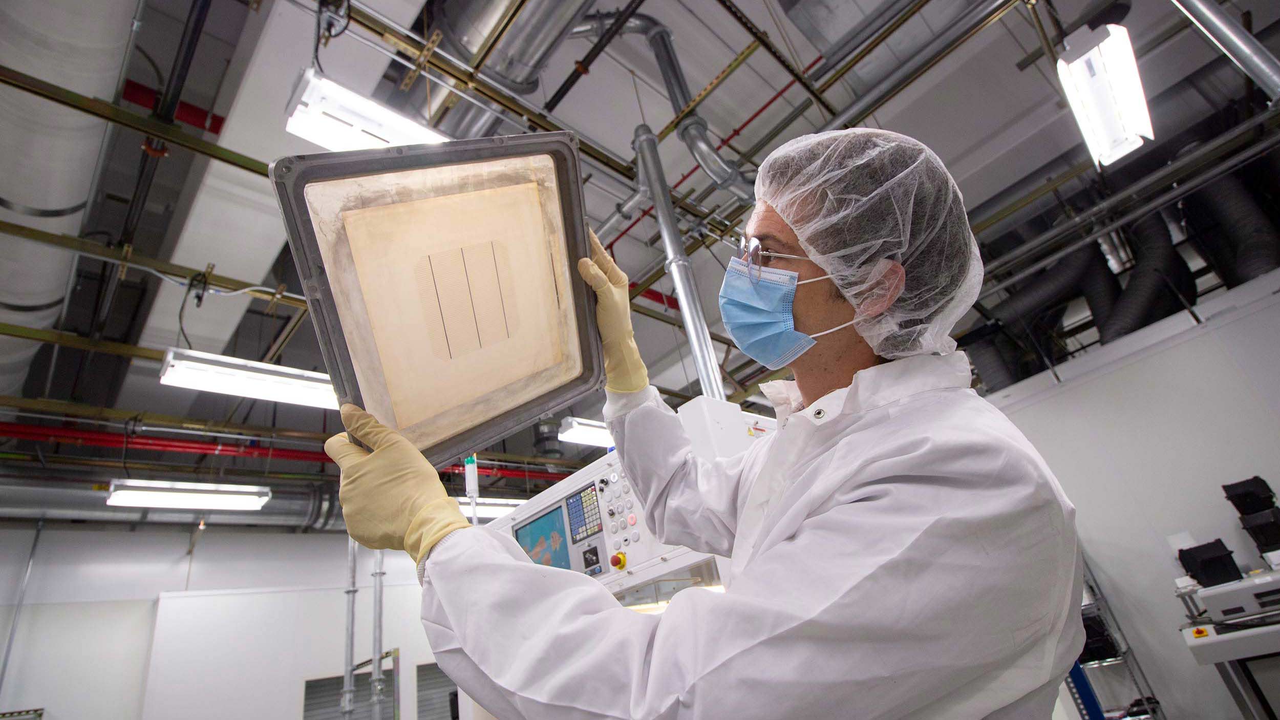 Zak Holman holding up a panel in a lab at MacroTechnology Works
