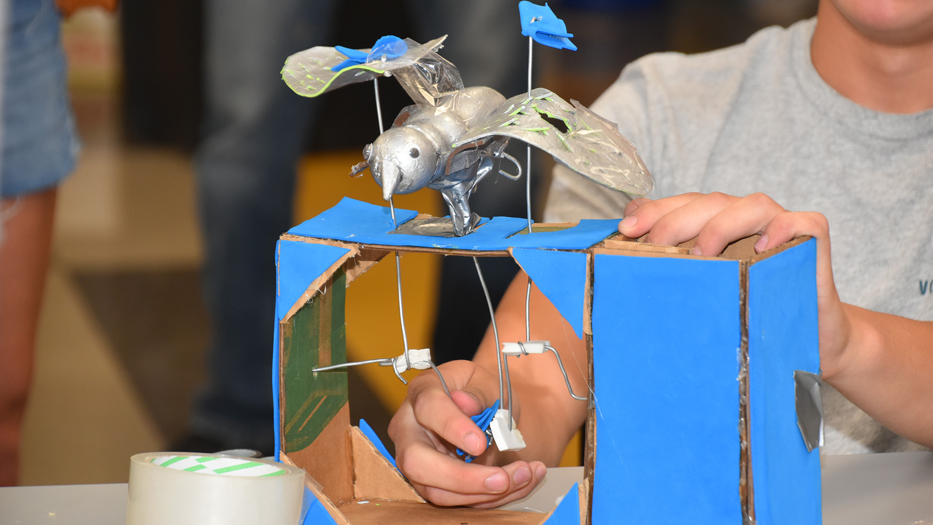 A child works on a robotic bird with flapping wings as part of a summer camp.