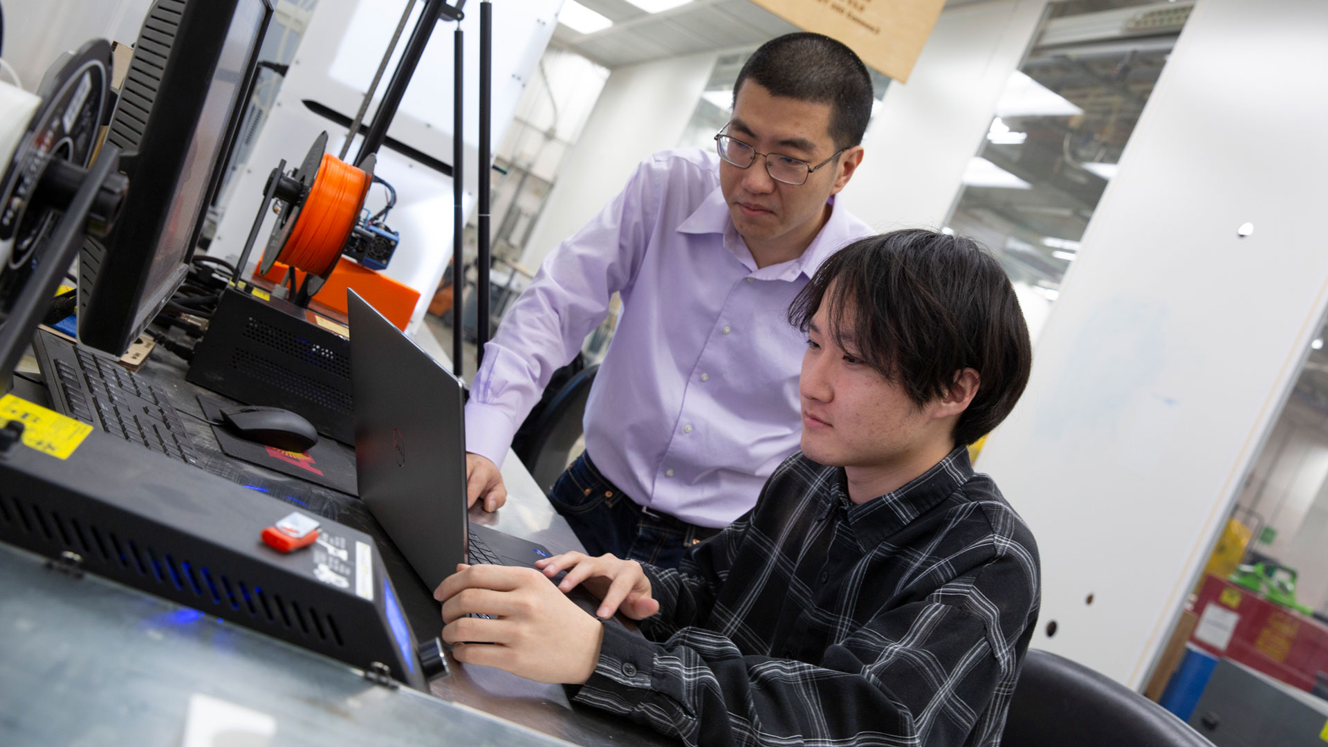 Zhengbin Chen (right), a senior engineering major focusing on the robotics concentration, works on an additive manufacturing model with his faculty mentor, Andi Wang, an assistant professor of manufacturing engineering.