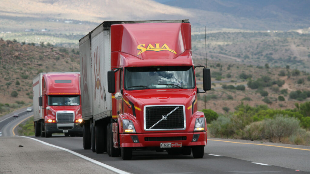 Two semi trucks driving on a two-lane highway.
