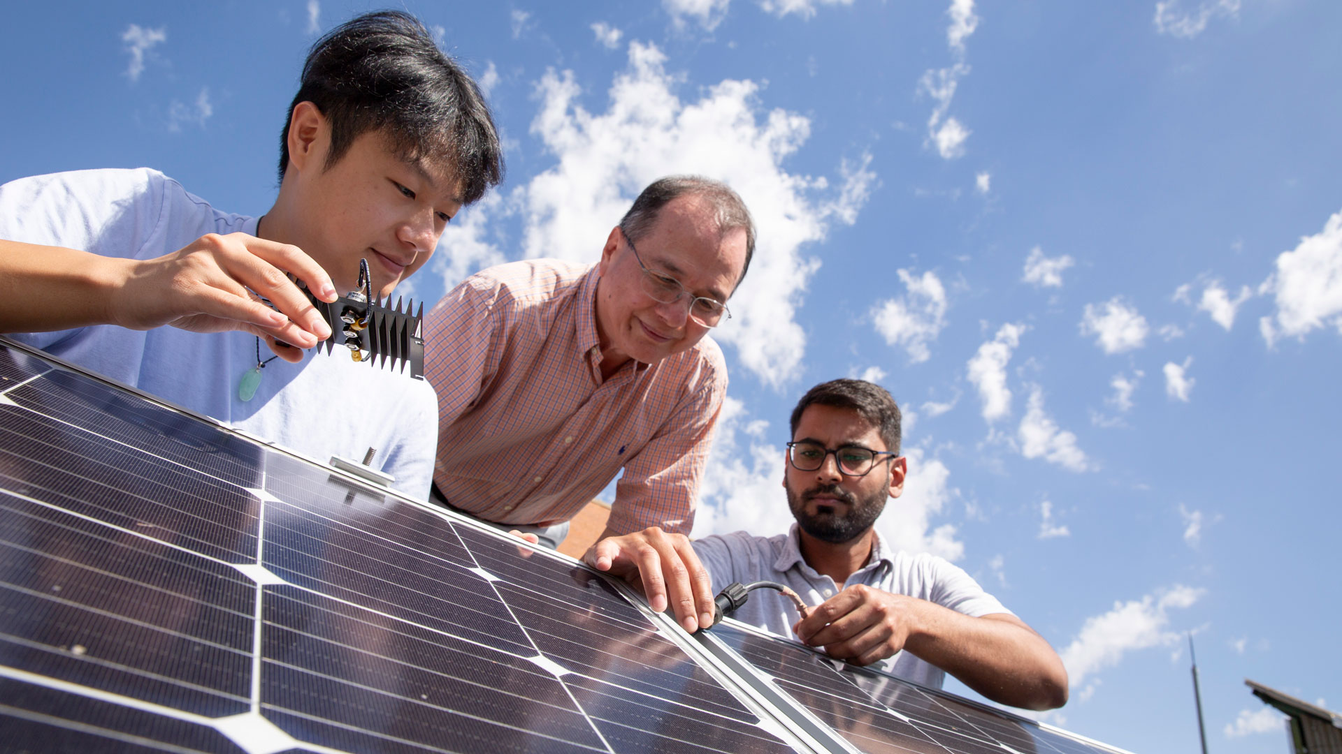 Meng Tao and Mike Ranjram with a student working on solar panels