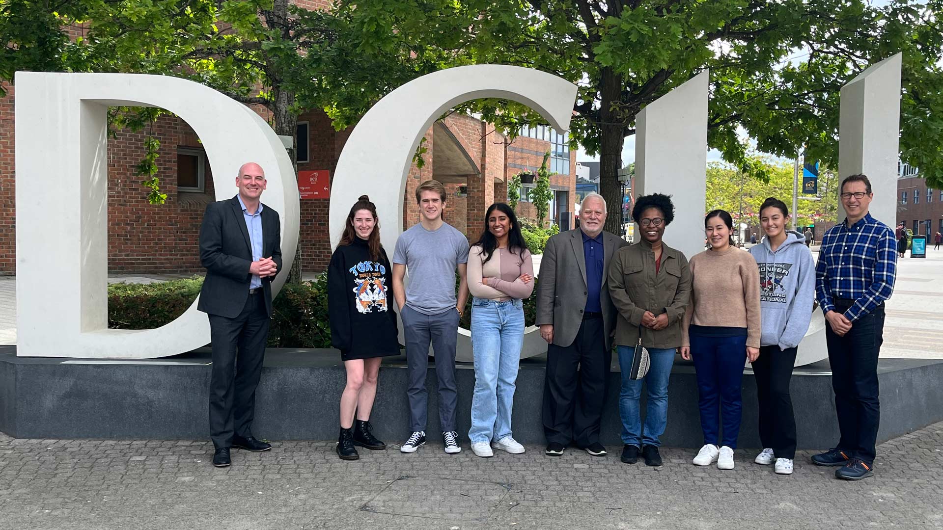students and faculty standing in front of DCU sculpture on Ireland's Dublin City University campus
