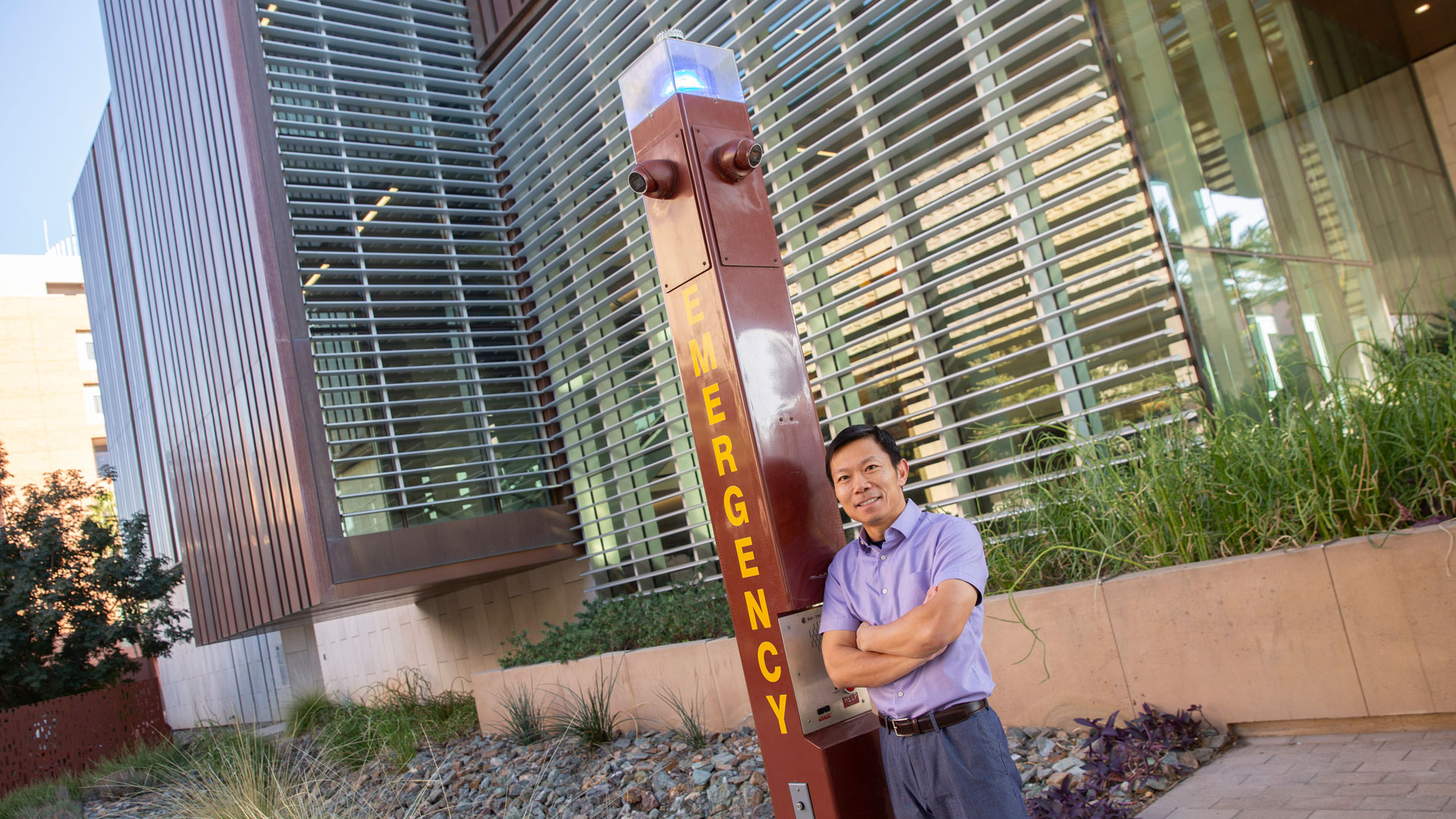 Ming Zhao stands next to an ASU campus blue light post.