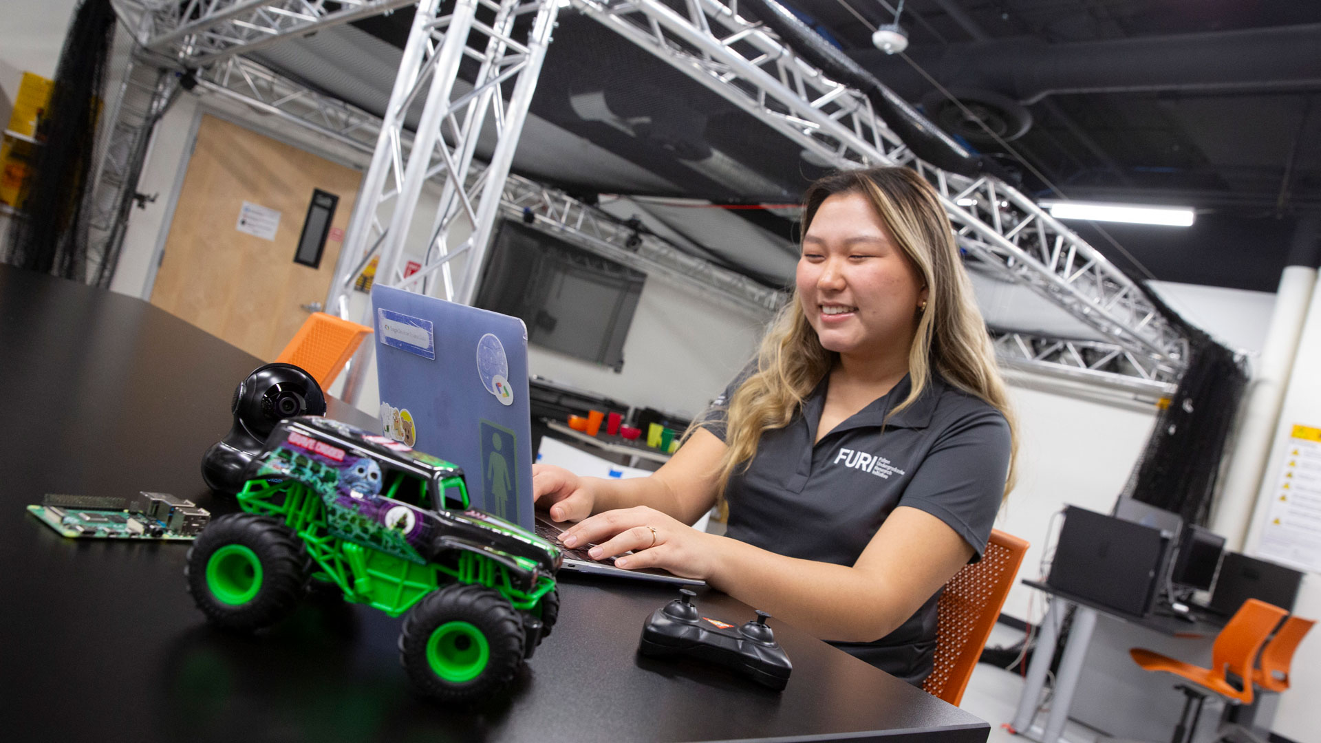 FURI student Jenna Jae Eun Lee works on a laptop with a remote control car in a project to use computer science to stop impaired driving.