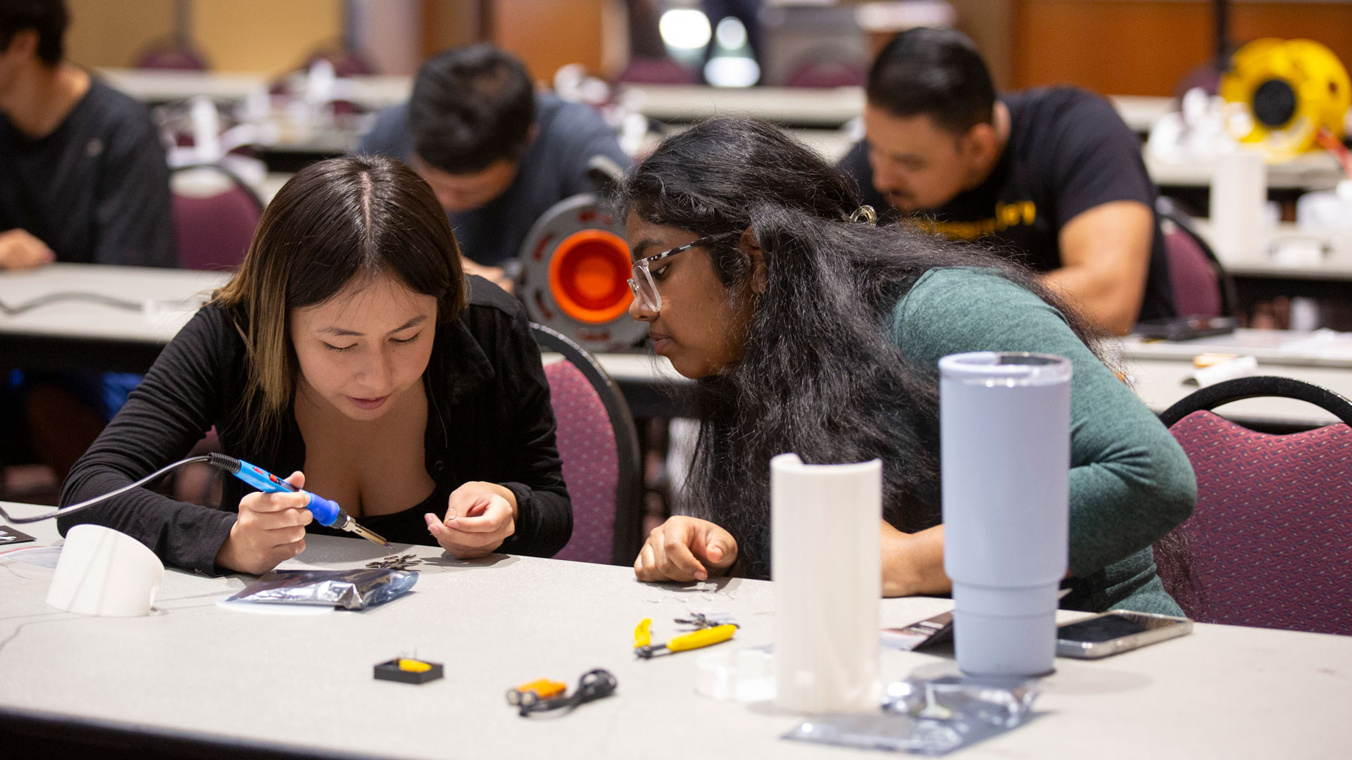 Two students work with electronic components at an ASU microelectronics workshop.