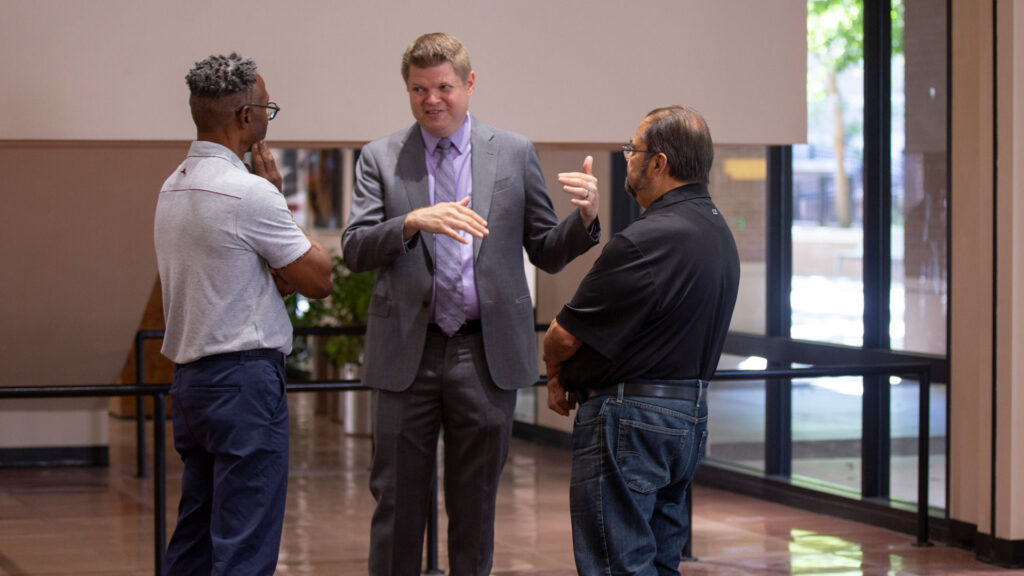 School of Integrated Engineering Interim Director Shawn Jordan talks with two other people at the microelectronics workshop.