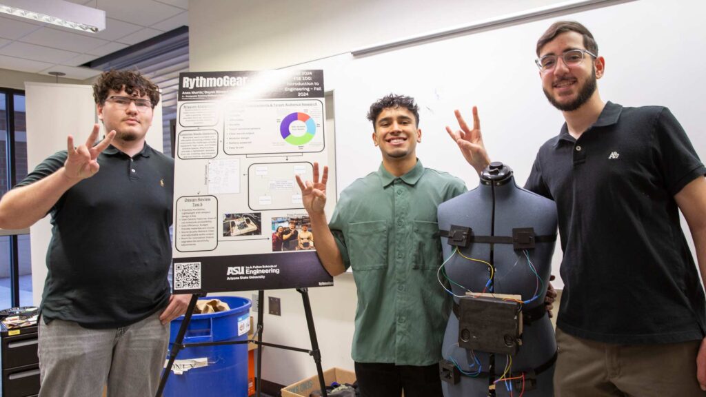 three students stand in front of their project poster