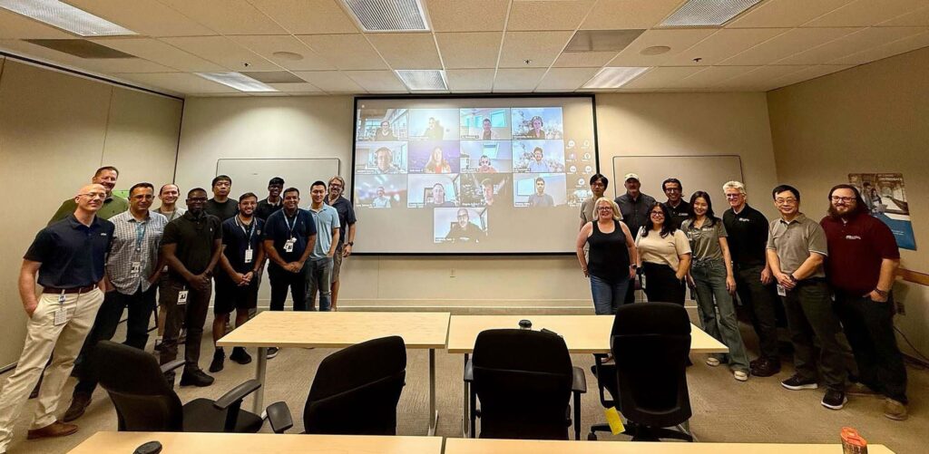 A group of people in a room with video conference participants on screen